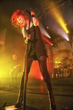 a woman with red hair on stage holding a microphone