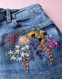 a pair of jeans with embroidered flowers on them