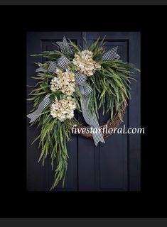 a wreath with flowers hanging on the front door