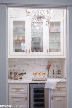 a kitchen with white cabinets and gold trimmings on the glass front cabinet doors