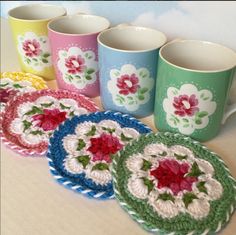 four crocheted coffee mugs are sitting next to each other on a table