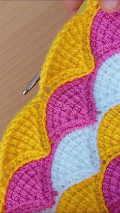 someone is crocheting the pattern on a piece of fabric with scissors in their hand