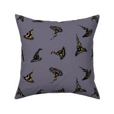 a gray pillow with black and gold witches on the front, sitting on a white surface