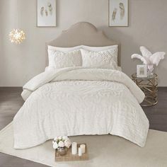 a bed with white comforter and pillows on top of it in front of two framed pictures