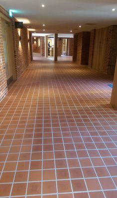 an empty hallway with brick walls and tiled flooring on either side of the door