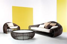 a living room with two chairs and a coffee table in front of a yellow wall