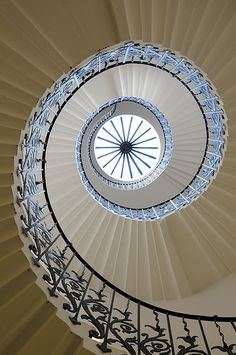 a spiral staircase in a building with blue glass railings on the top and bottom