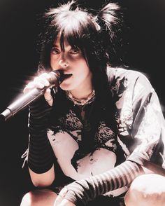 a woman with black hair is holding a microphone