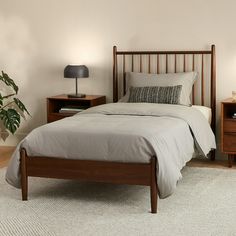 a bedroom with a bed, nightstands and a plant on the side of the bed