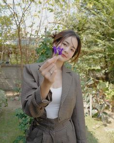a woman holding a purple flower up to her face