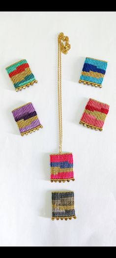 four pieces of colorful beaded jewelry on a white surface with a gold chain hanging from it