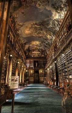 a long room with many bookshelves and ceilings painted in gold, blue, and green