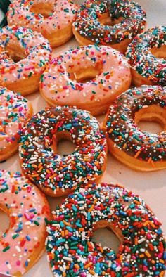 there are many donuts with sprinkles on them in the box and ready to be eaten