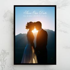 a couple kissing in front of the sun with their wedding photo on it's back