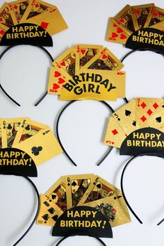 six birthday hats with playing cards and happy birthday written on the front, in gold foil