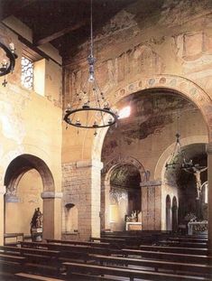 the interior of an old church with pews and chandeliers hanging from the ceiling