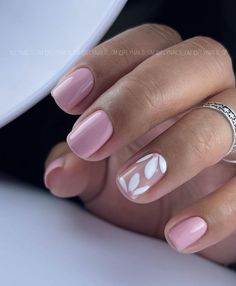 a woman's hand with pink and white manicures on her nails, holding a ring