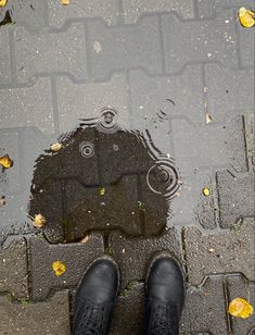 a person standing in front of a puddle with their feet up on the ground and black shoes