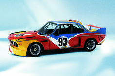 an old race car painted in red, yellow and blue with numbers on the side