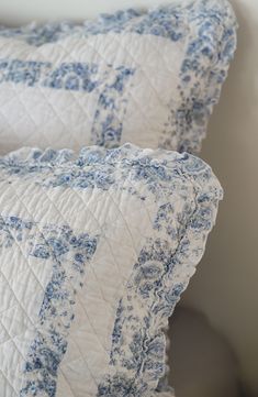 two blue and white pillows sitting next to each other