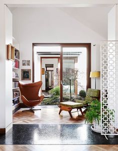 a living room filled with furniture next to a window covered in plants and bookshelves