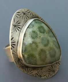 an old silver ring with green stone in the center and stars around it, on a gray background