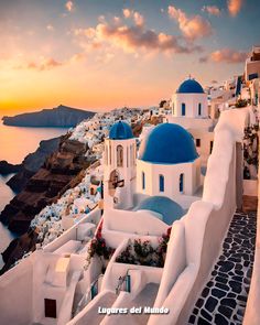 the sun is setting over an island with white buildings and blue domes