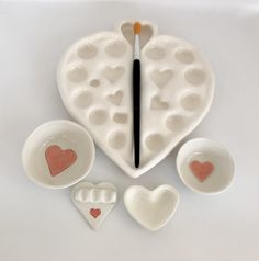 heart shaped bowls and spoons are arranged in the shape of an egg carton