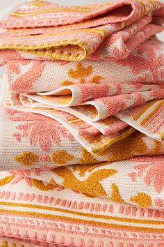 folded towels stacked on top of each other in pink and yellow colors with white trim