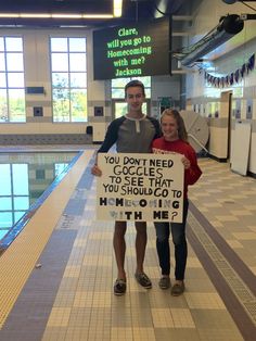 two people standing next to each other holding a sign that says you don't need to see that you should go to swimming with me