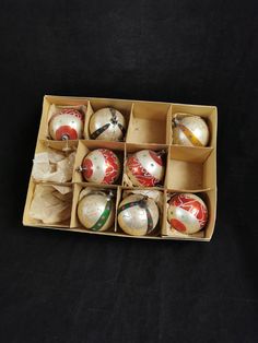 an open box filled with christmas ornaments on top of a black tablecloth covered floor