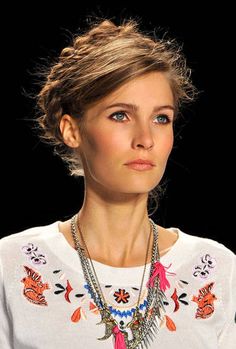 a woman wearing a white sweater and colorful necklaces on her neck, looking off to the side