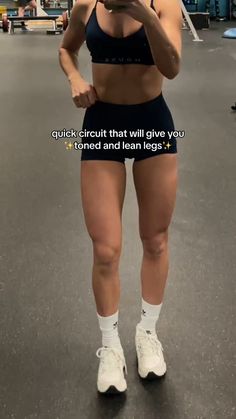 a woman is standing in the gym with her cell phone