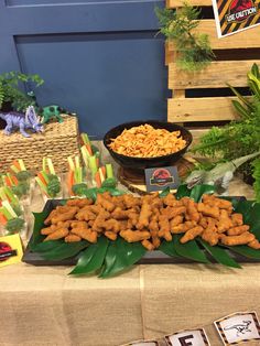 a table topped with lots of food next to green plants and baskets filled with carrots