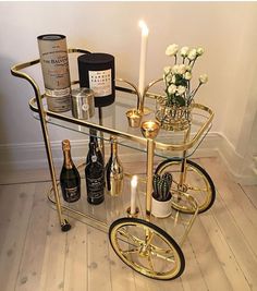 a gold bar cart with wine bottles and candles