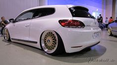 the rear end of a white car with gold rims on display at an auto show