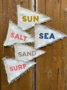 three sail flags with the words sun, salt, and surf on them