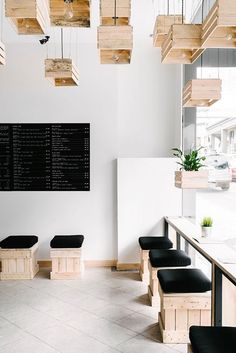 the inside of a restaurant with black and white chairs, wooden tables and hanging planters