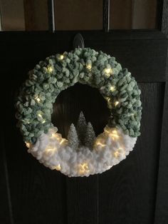 a wreath with lights hanging on the front door