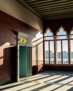 an open door in the middle of a room with large windows and sunlight coming through