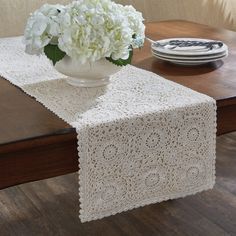 a vase with white flowers sitting on top of a wooden table next to a plate