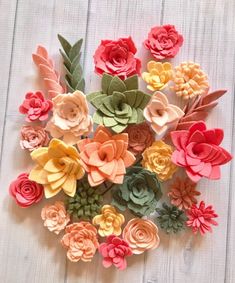 paper flowers are arranged on a white wooden surface