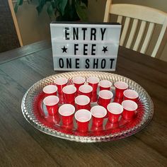 a tray with cups and a sign that says entry fee one shot on the table
