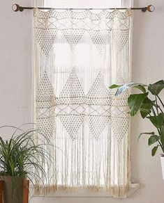 two potted plants sitting on top of a wooden shelf next to a window curtain