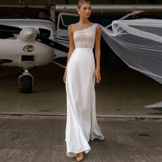 a woman standing in front of an airplane wearing a wedding dress with sheer veils