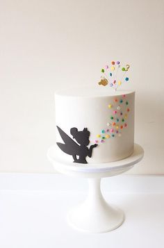 a white cake with black silhouettes and colorful sprinkles on the top