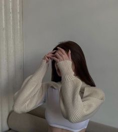 a woman sitting on the floor covering her face with both hands