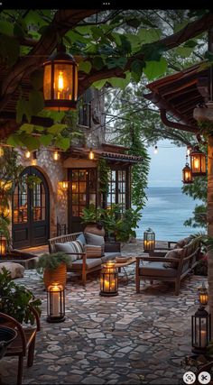 an outdoor living area with candles lit up in front of the house and water behind it