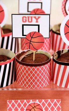 cupcakes in paper cups with basketball signs on them and decorations for the table