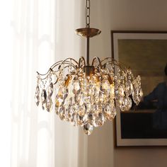 a chandelier hanging from the ceiling in a room with white walls and curtains